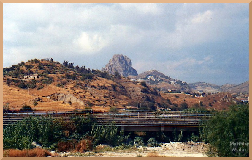 Felsen mit altgriechischen Dörfern, Mélito di Porto Salvo, Straße und braungedörrter Hügel im Vordergrund