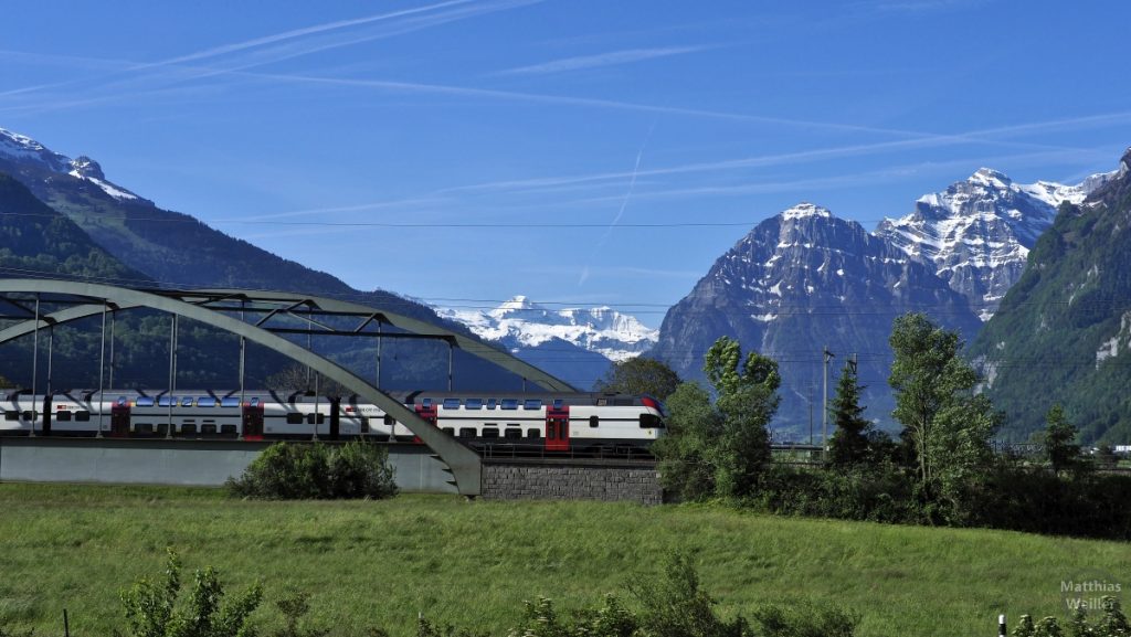 Panorama schneebedeckte Glarner Alpen mit Eisenbahnbrücke und Doppelstockzug