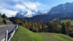 Beschneiter Bergstock mit Herbstatmosphäre un Straße im Vordergrund, Engelberg-Anfahrt