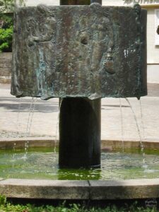 Koaxialer Bronzebrunnen mit umlaufenden Tonkrugfrauen als Bildmotiv