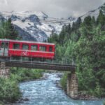 Roter Bahnwagen mit Velosymbol über Bergbach mit Gletscherkulissse