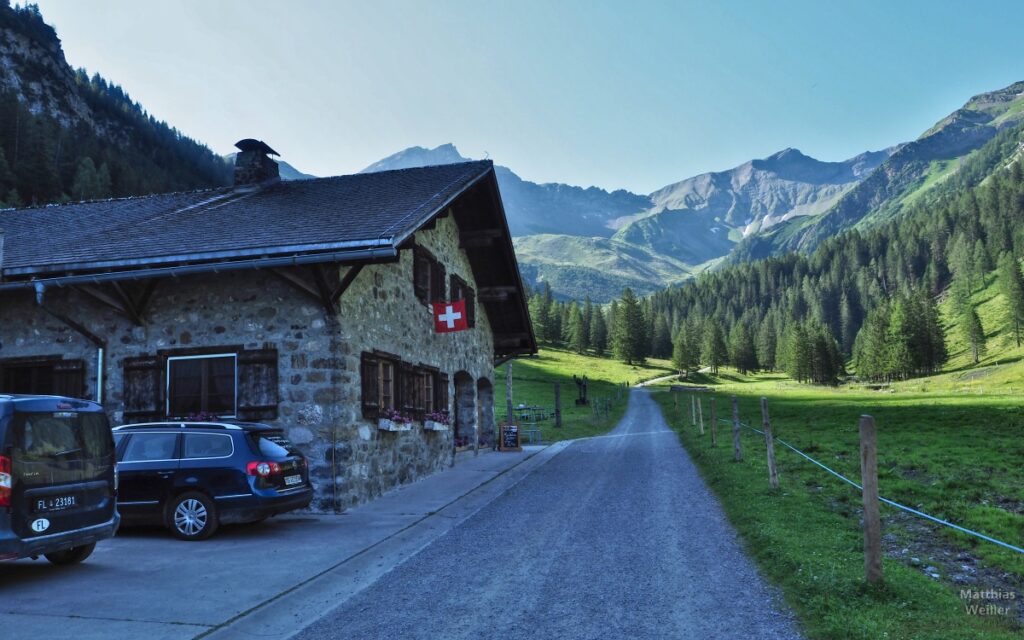 Steinhaus Alp Valüna mit Schweizer Flagge und Bergarena im Hintergrund