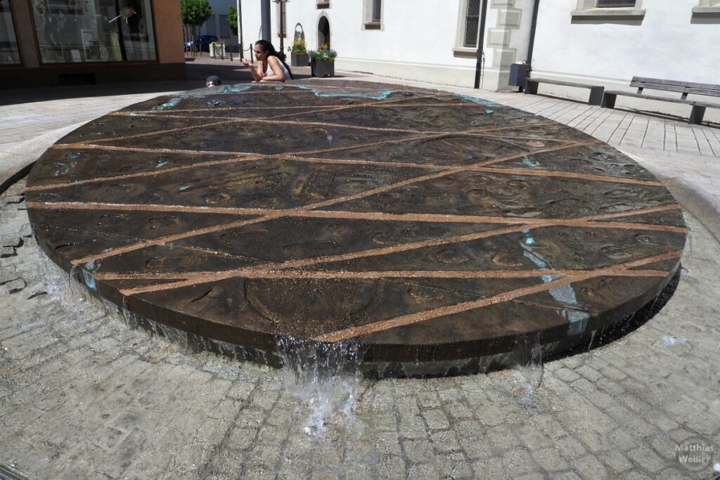 Brunnen als abgeschrägter Flachstein mit Zeichenmustern