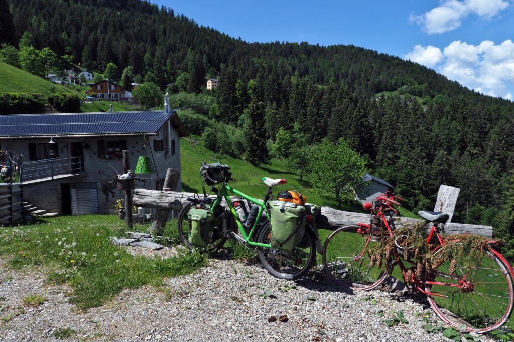 Grünes Reiserad neben rotem Altrad mit Tannenzapfen