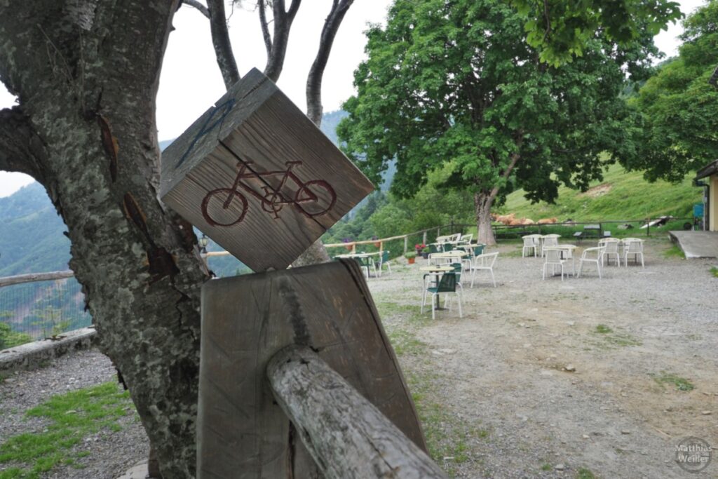 Holzklotz mit Fahrradsymbol für Veloständer beim Gasthof Alpe Neggia