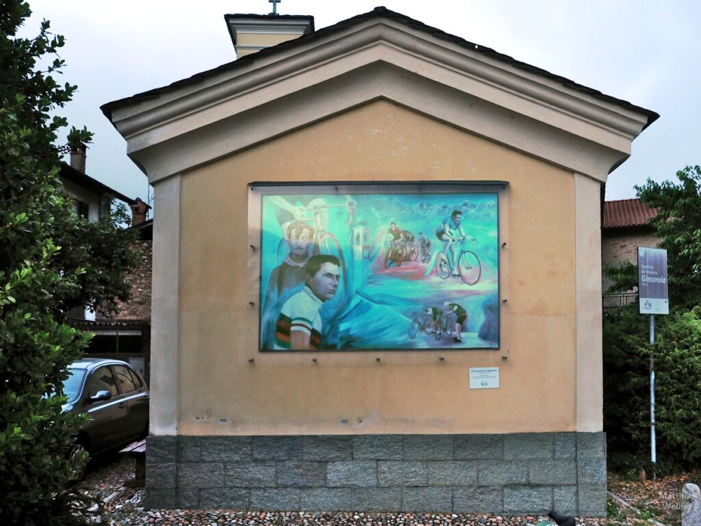 Muralo "I volti della legenda" mit Alfredo Binda, Fausto Coppi Gino Bartali, Ferdi Kübler und Kirchturm Brinzio