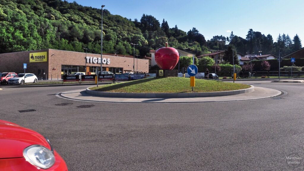 Verkehrskreisel in San Fermo mit Skulptur roter Apfel, bei Tigros-Supermarkt