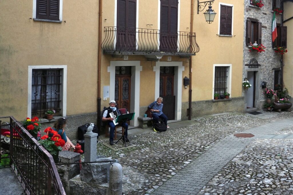 Akkordeonspieler und zwei Frauen auf einem Platz in Ponna Superiore