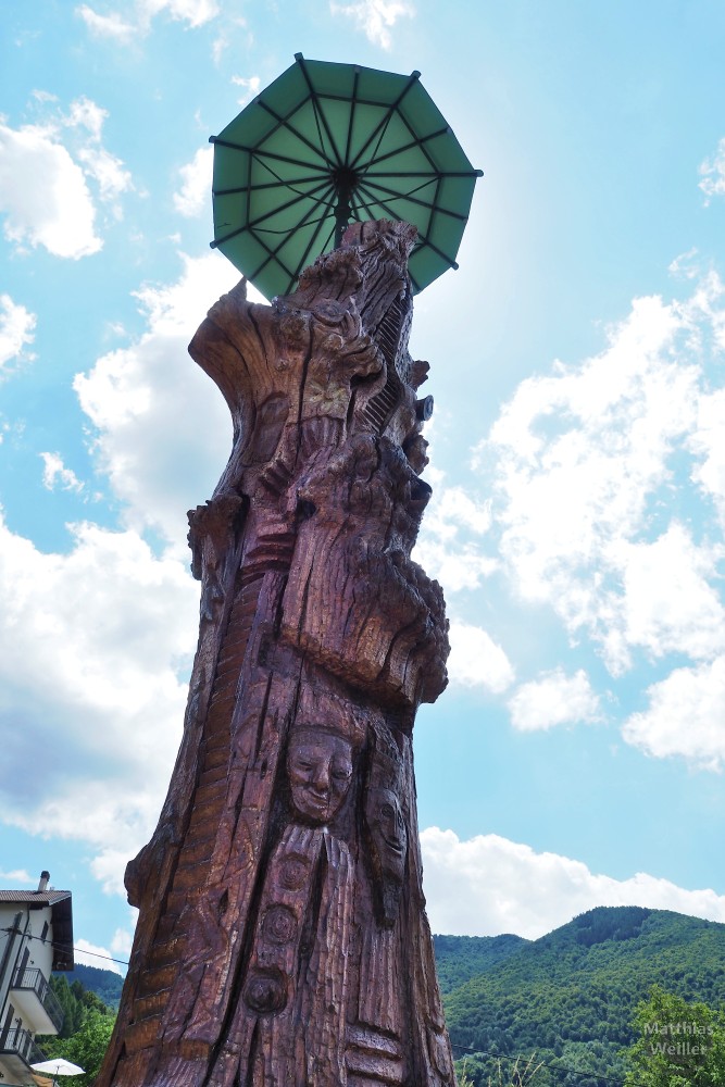 geschnitzte Holzskulptur mit grünem Regenschirm