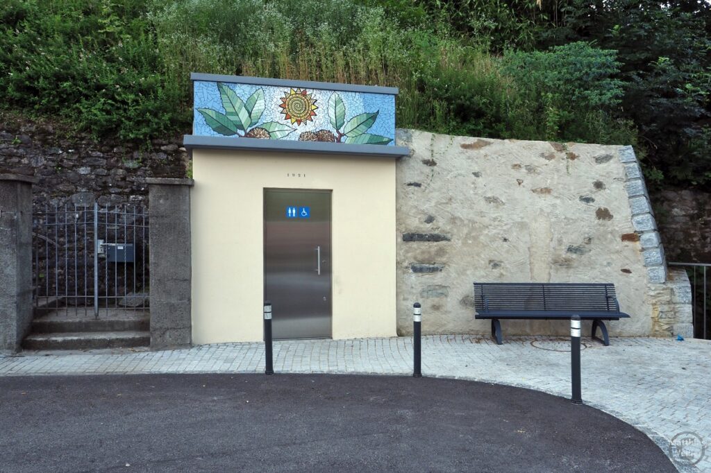 öffentliche Toilette mit buntem Mosaik über der Tür in Pura