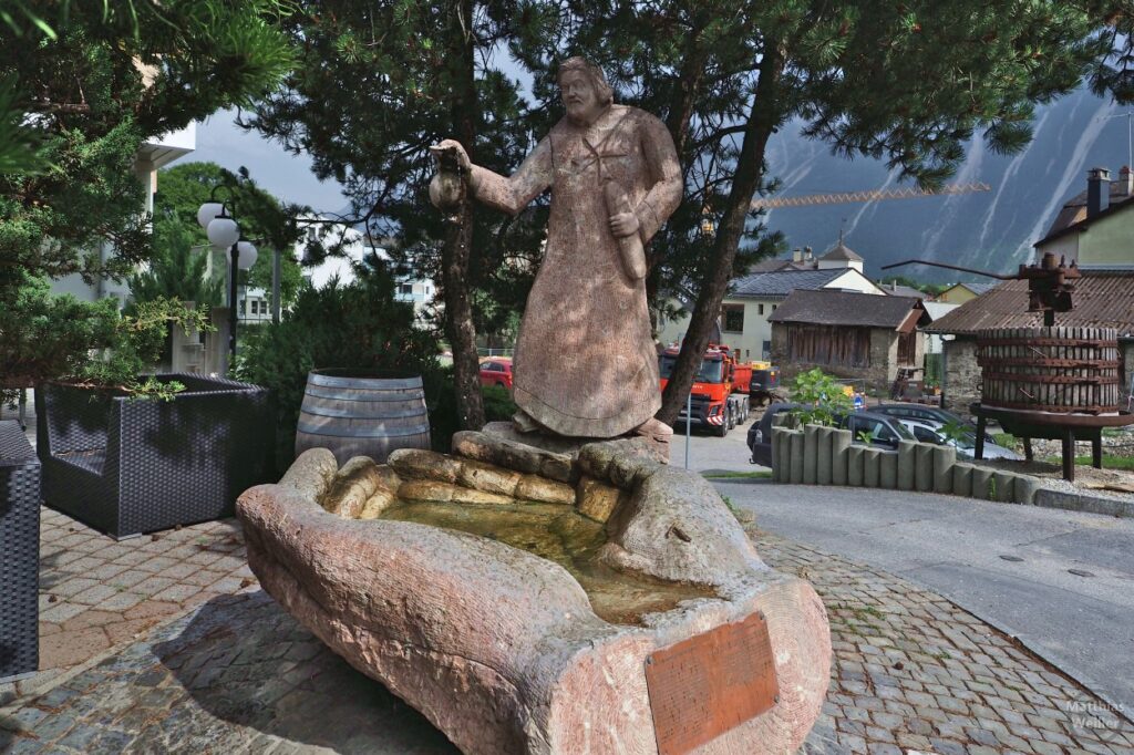 Brunnen als Hand geformt mit Skulptur Mann mit Krug und Brot