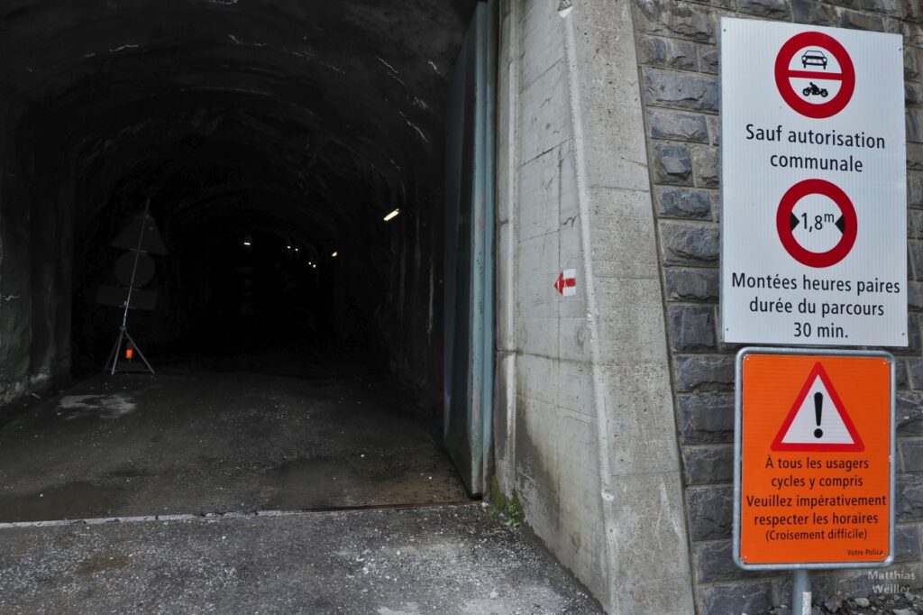 Tunnelportal unten mit Warnschildern, u.a. für Radler