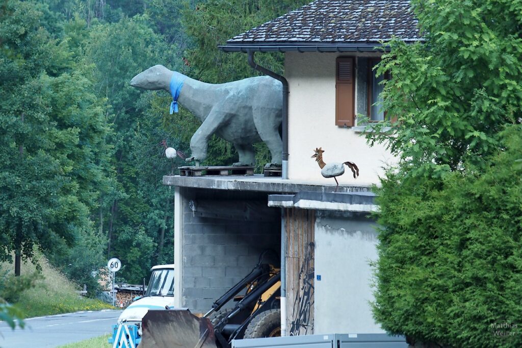 Dinosaurierskulptur auf Garagenterrasse eines Hauses