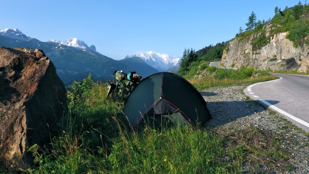 Zelt und Velo neben Straße und Blick auf Mont-Blanc-Massiv