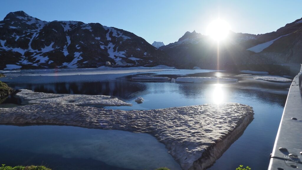Totensee Grimselpass mit Eis- und Schneeresten und Abendsonne im Gegenlicht