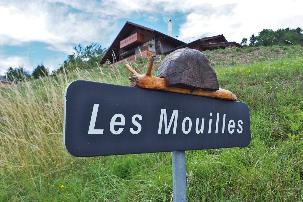 Holzschnecke auf Ortschild "Les Mouilles"