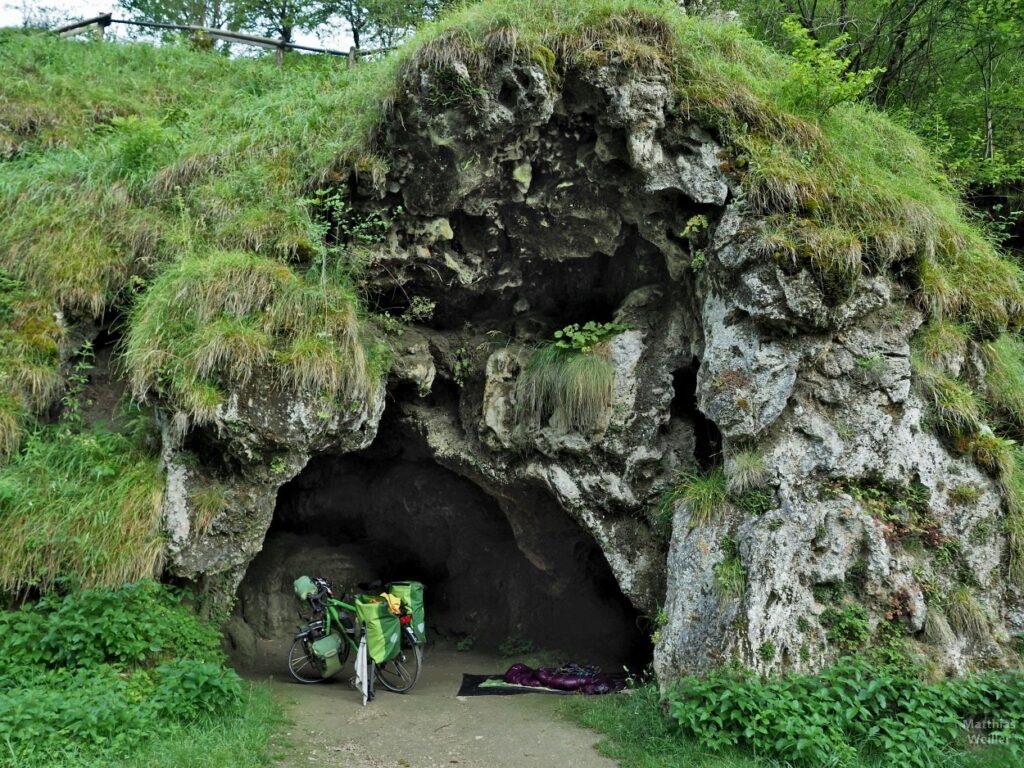 Höhle mit Schlafsack und grünem Reiserad