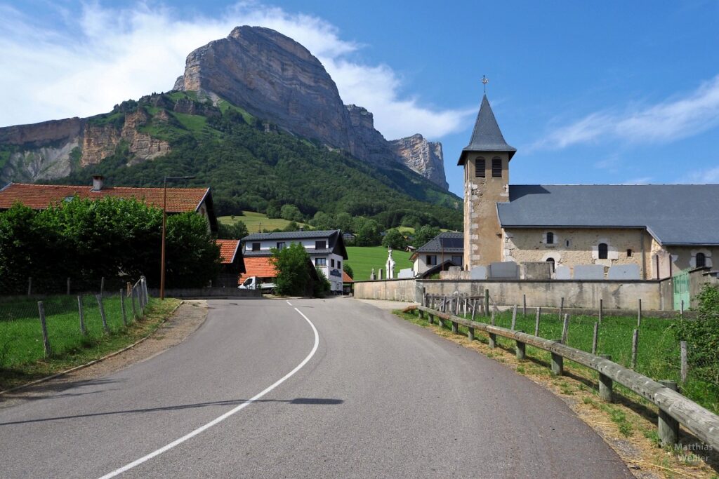 Dorfeinfahrt mit Kirche, imposant aufragender Felsgrat im Hintergrund, St-Pancrasse/Plateau-des-Petites-Roches, Chartreuse