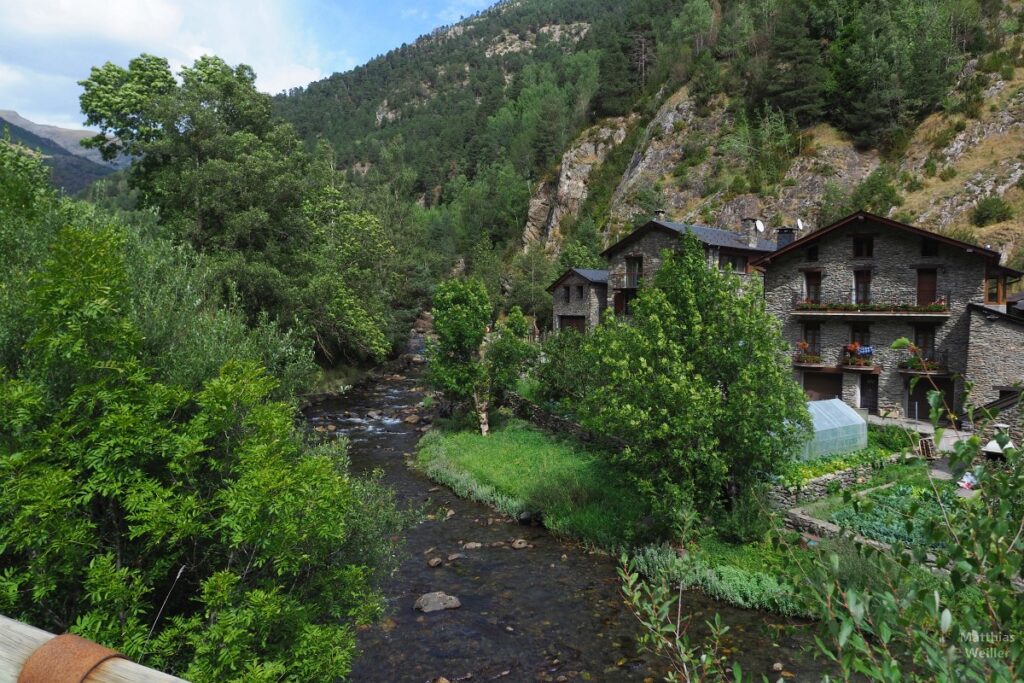 Bergtal mit Bergfluss, Laubbäumen und typischen Steinhäusern in Andorra (Ansalonga)