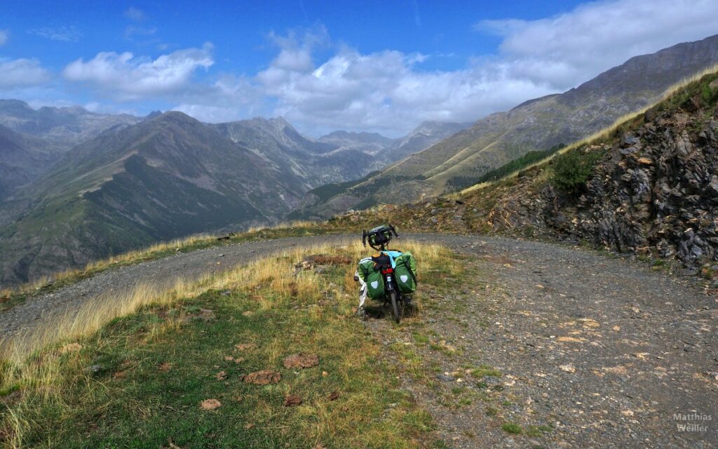 Pistekurve mit Reiserad mittig, Panorama auf die Berge von Aiguëstortes/Sant Maurici