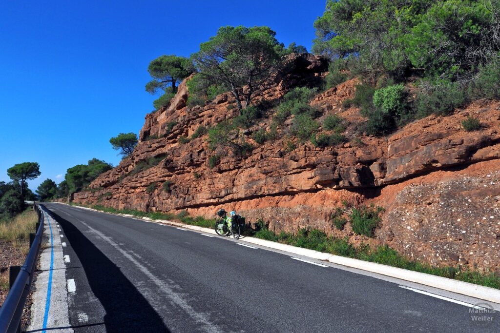 rote Feslwand an Straße mit grünem Reiserad, Sant Llorenç i Munt de l'Obac