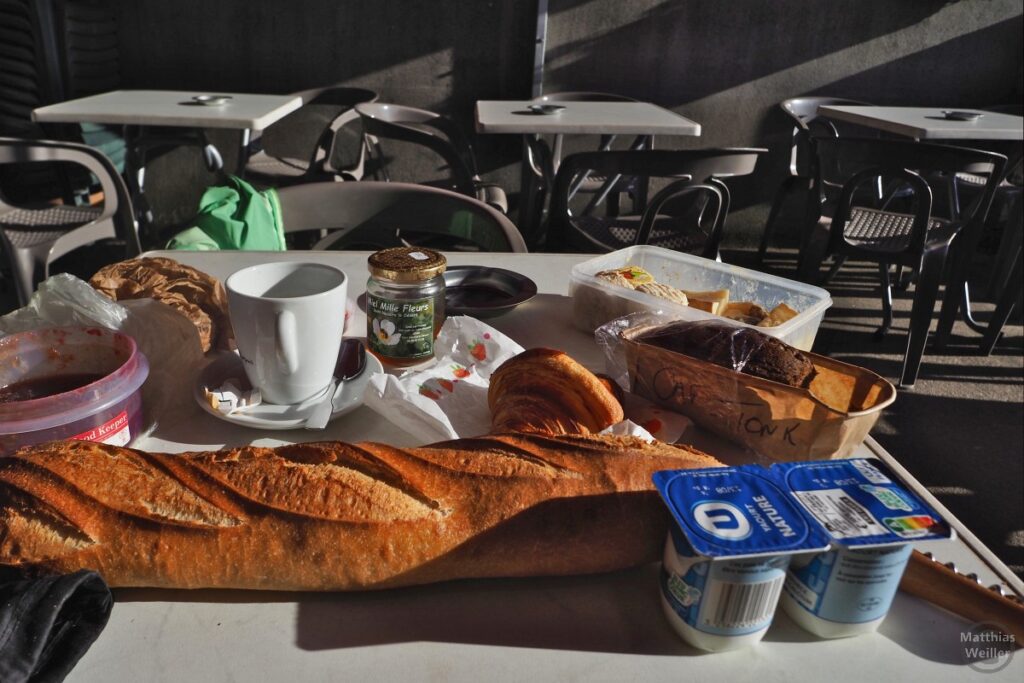 Selbstversorgerfrühstück auf Terrasse, mit Gastrokaffee, Baguette,2 Joghurts, Käsebox, dunkler Rührkuchen, Croissant, Marmelade, Honigglas
