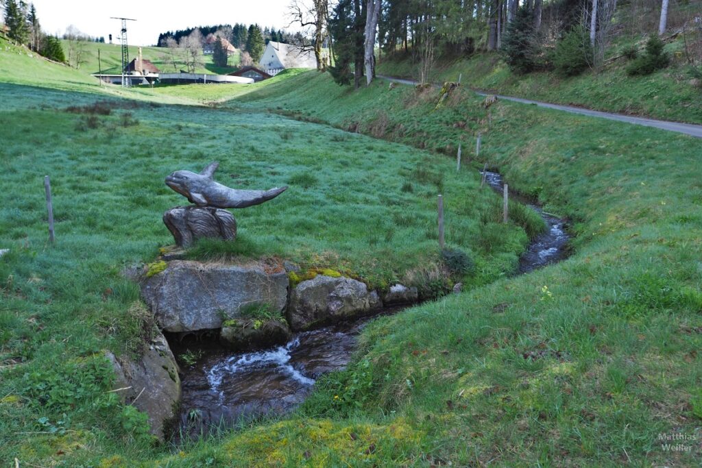 Jungfräulicher Bregenbach in Bergwiese mit geschnitztem Holzdelphin