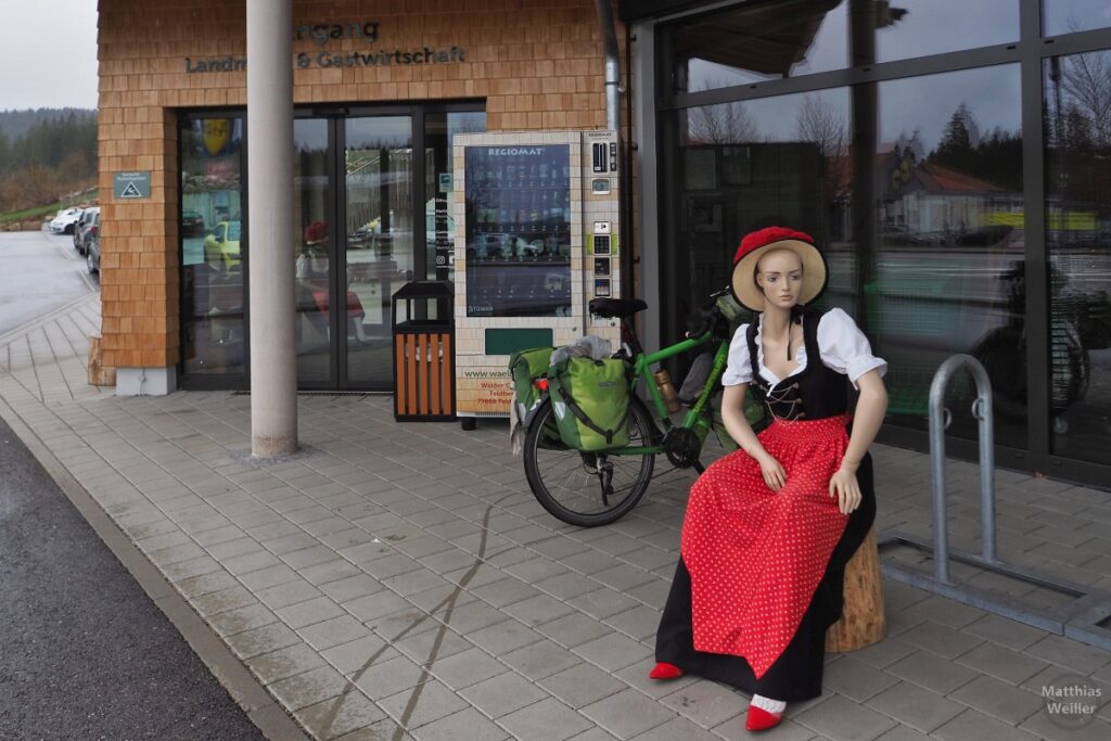 Schwarzwaldmädelpuppe vor Souvenirgeschäft und Restaurant