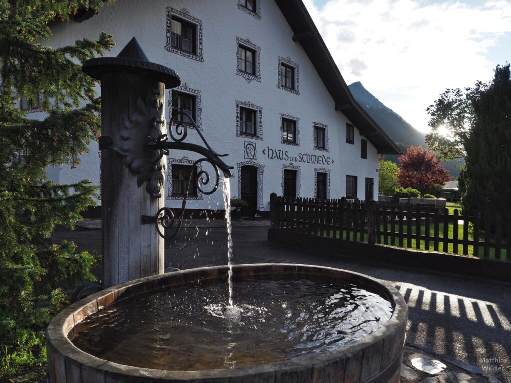 Brunne vor Haus zur Schmiede im Gegenlicht