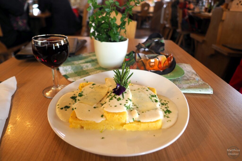 Polenta mit Bergkäse, Rosmarinzweig und Glas Wein