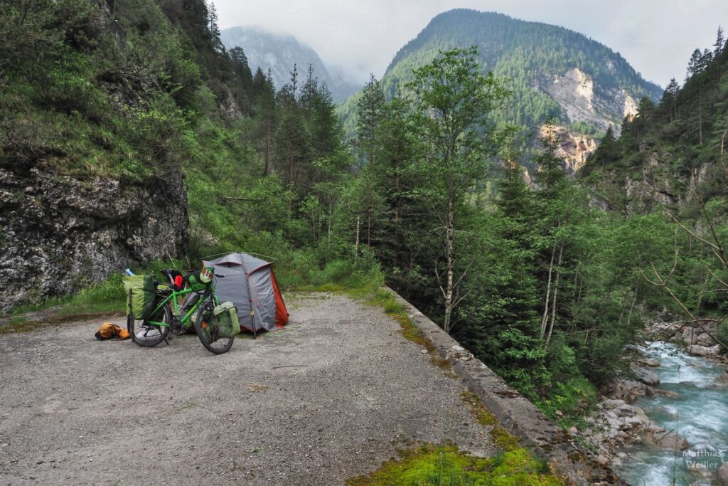 Zelt und Velo auf Betonbrücke über Fluss