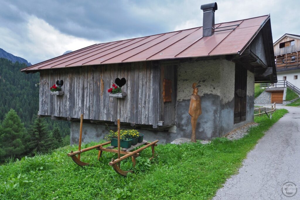 Haus mit Holzschnitzherzen in der Fassade, Skulptur und Schlitten