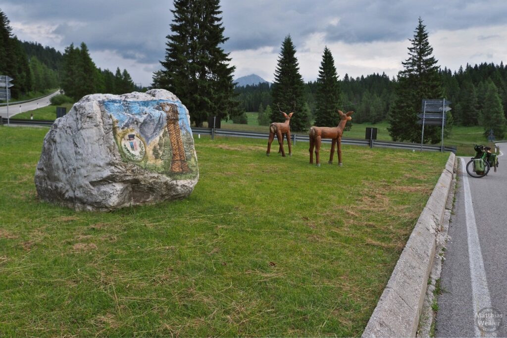 bemalter Steinblióck und zwei Holztiere an Straßenkreuzung, Passo San Antonio