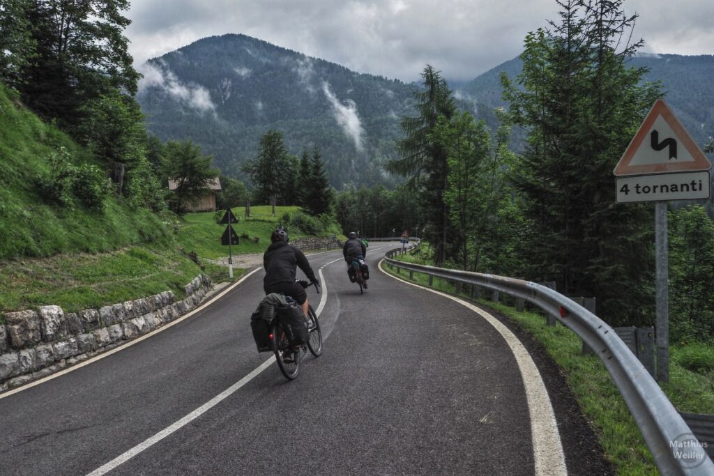 Drei Reiseradelr auf Abfahrt am Passo della Mauria, abdampfende Wolken