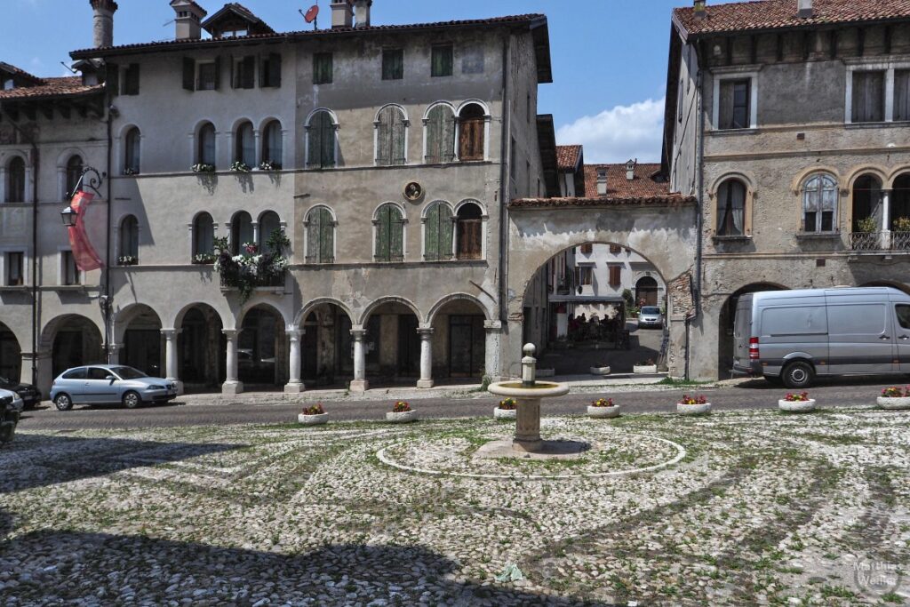 Feltre mit Pflasterplatz und Brunnen, hsitorischen Häuser mit romansichen Fenstern, Säulenkolonnaden