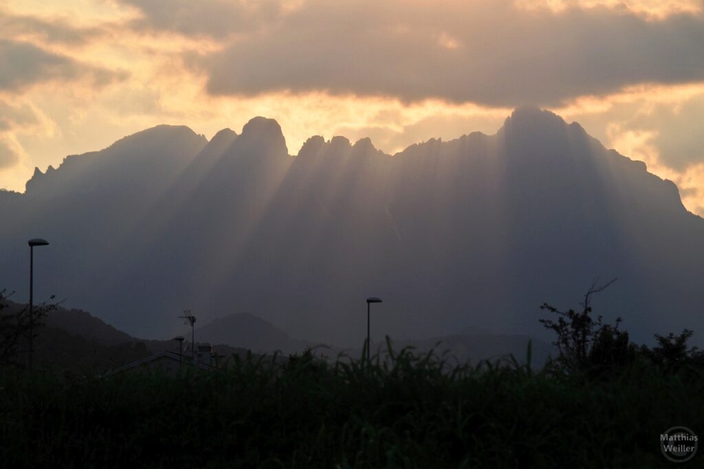 Berg im streifigen Gegenlicht, Wolken vor Sonne