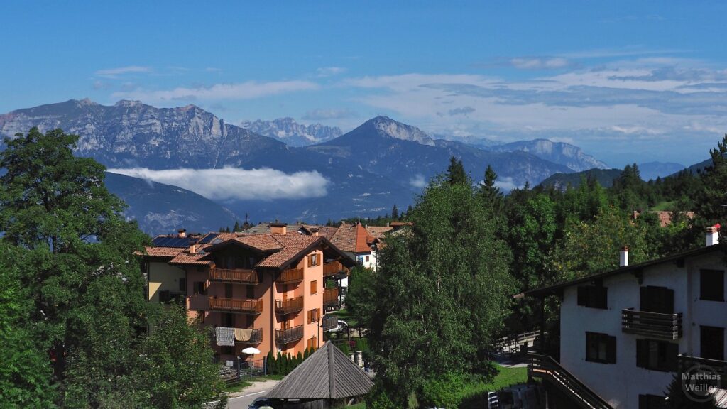 Ausblick von Serrada über Häuser zum Monte Baldo und Brenta-Gruppe