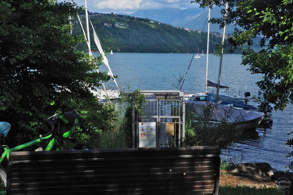 Blick vom Ufer auf den Lago di Caldonazzo mit Segelbooten am Anleger