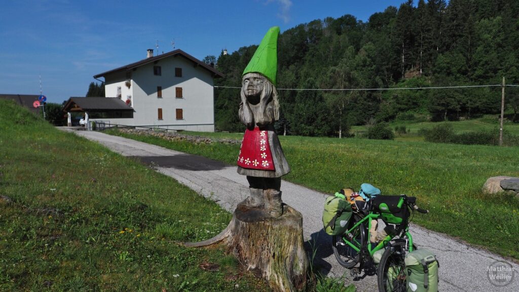 Holzzwergskulptur mit roter Schürze und grünem Zipfelhut