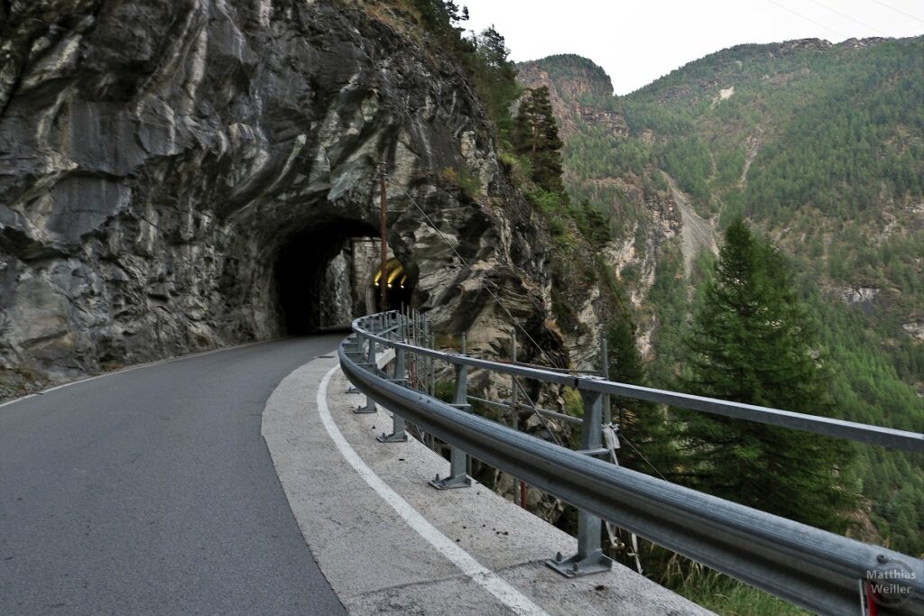 Straße mit Leitplanke und Felstunnel