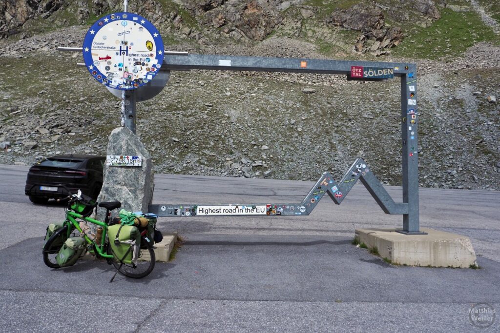 Stahltor mit Stein und Schild "Ötztaler Gletscherstraße - Highest road in the EU", mit Velo