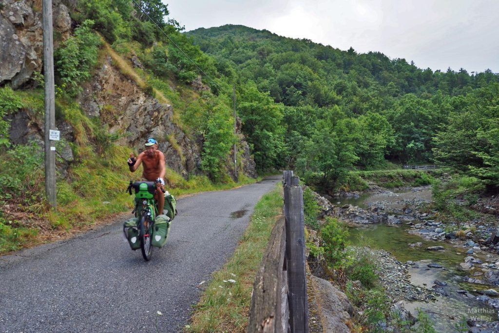 Selbstporträt auf Reisvelo fahrend neben Flusslauf, Alta Valle Erro